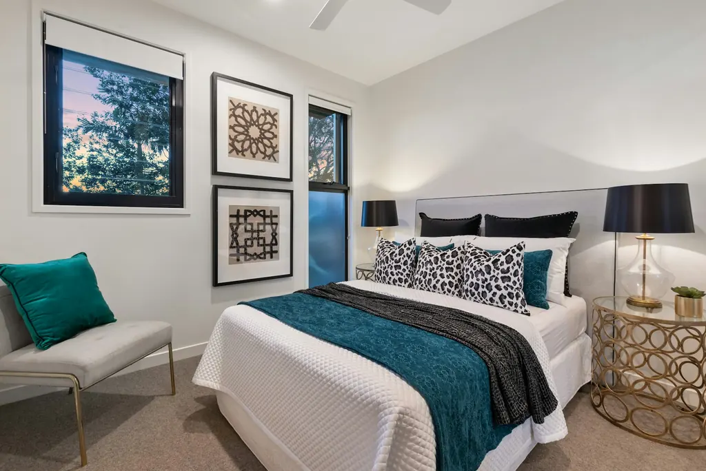 Bedroom with timber bedside furniture, framed prints and blue cushions