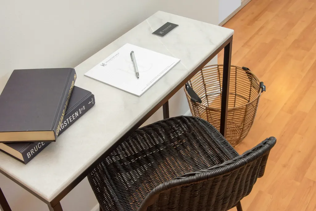 Home study with a desk, notebooks and a woven chair