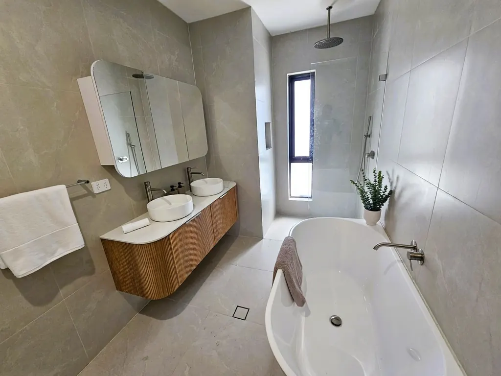 Milestone bathroom with a bath, timber vanity and tall window