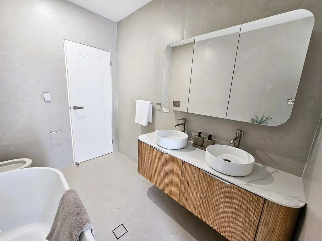 Milestone bathroom with a double-basin timber vanity and mirrored cabinets