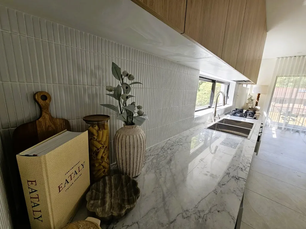 Milestone kitchen worktop with a textured tiled splashback and timber overhead cabinets