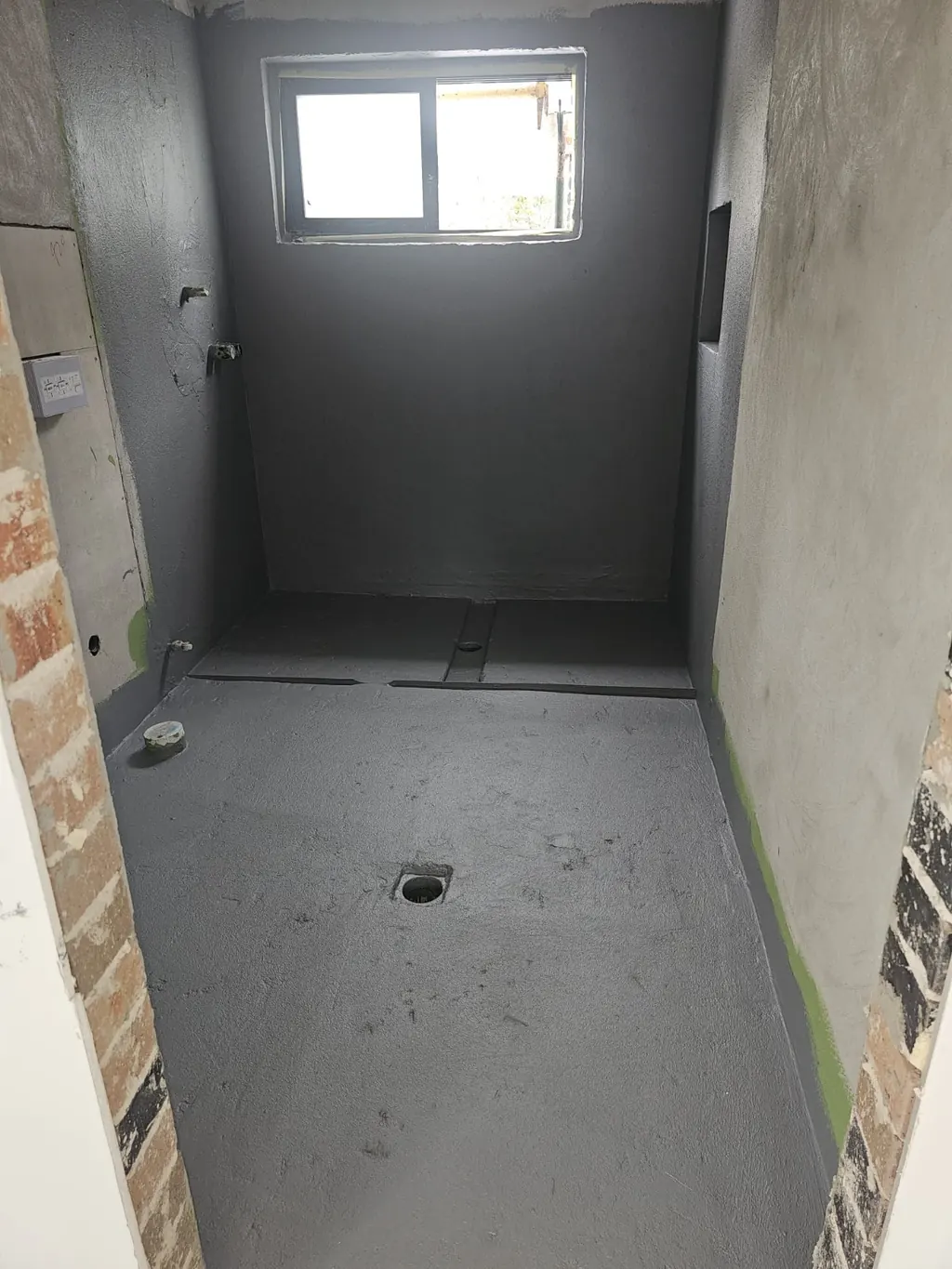Milestone shower enclosure in progress with coated walls and an unfinished floor