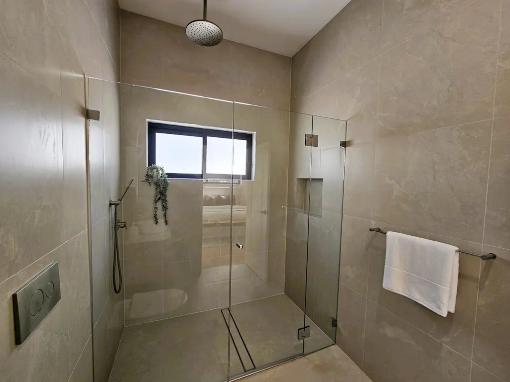 Milestone tiled shower with a ceiling-mounted showerhead and glazed screen