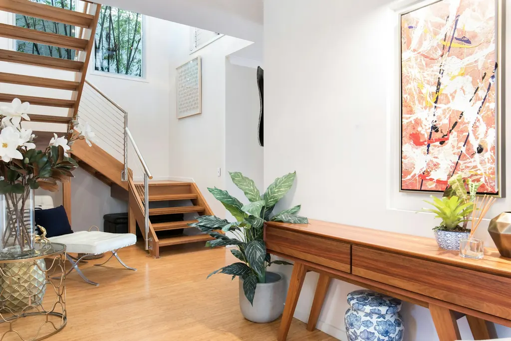 Timber staircase beside a furnished living space and indoor plants
